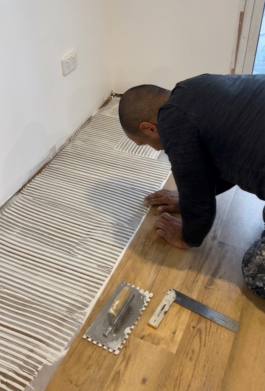 Tradesman installing tiles in a modern bathroom renovation
